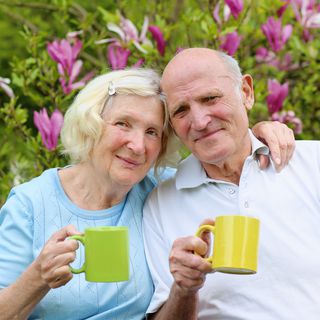 image of a couple smiling and hugging while holding cups of tea